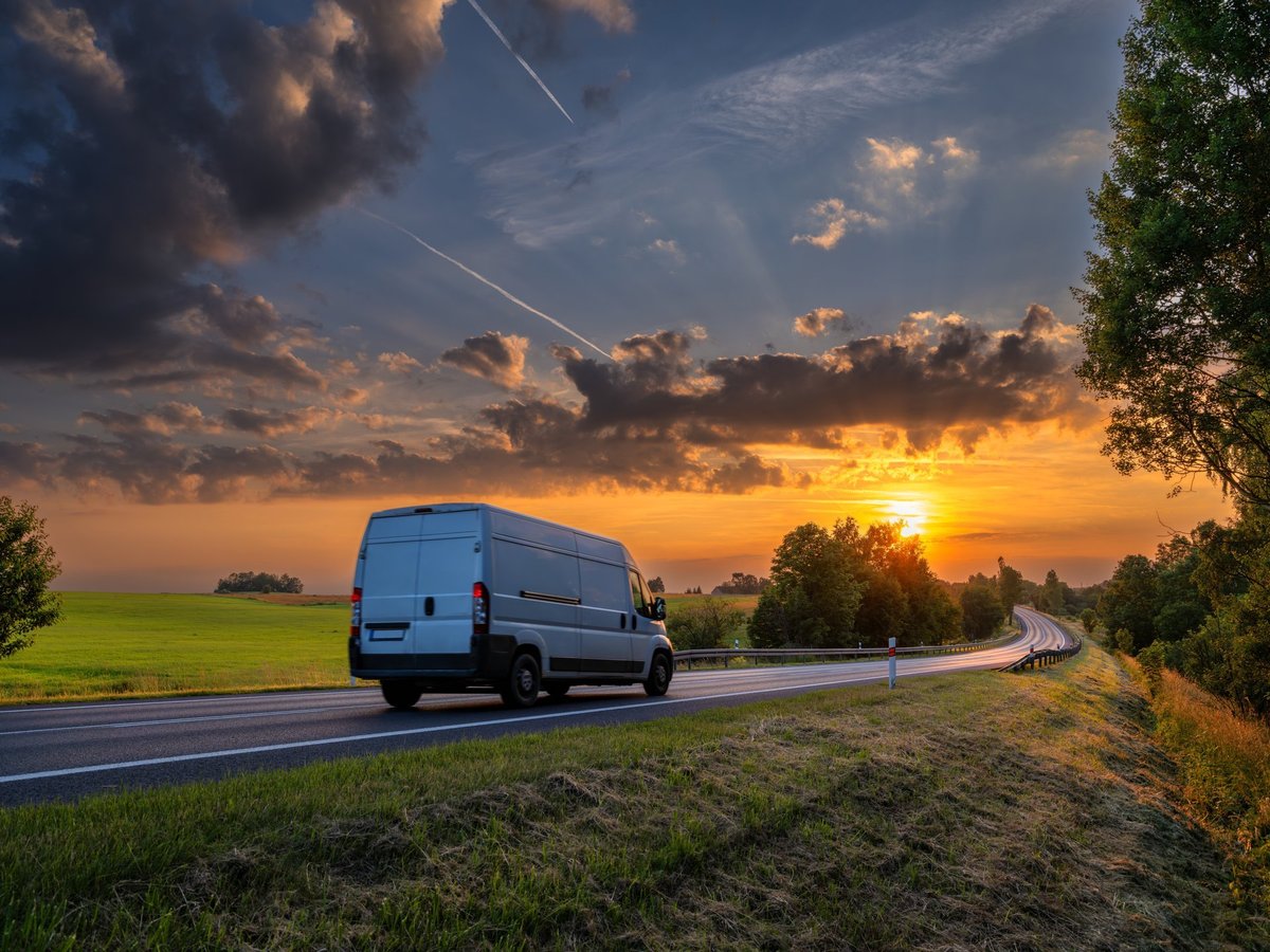White box truck driving along a road at golden dusk